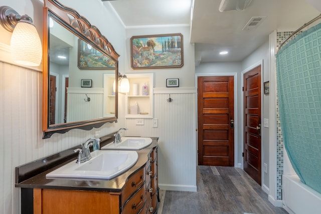 bathroom featuring double vanity, shower / bath combination with curtain, wood finished floors, and a sink