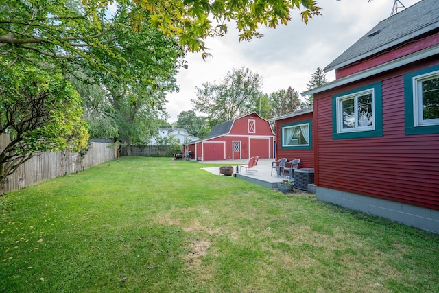 view of yard with a barn, a garage, a fenced backyard, an outbuilding, and central air condition unit