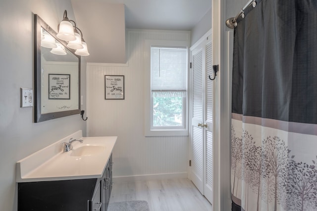 full bathroom with baseboards, wood finished floors, and vanity