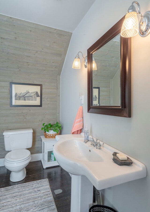 bathroom with lofted ceiling, toilet, and wood finished floors