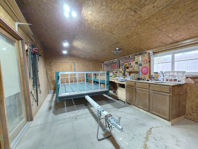 misc room with lofted ceiling, a workshop area, and concrete flooring