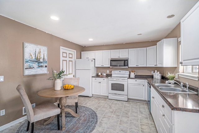 kitchen featuring stainless steel appliances, dark countertops, white cabinets, a sink, and baseboards