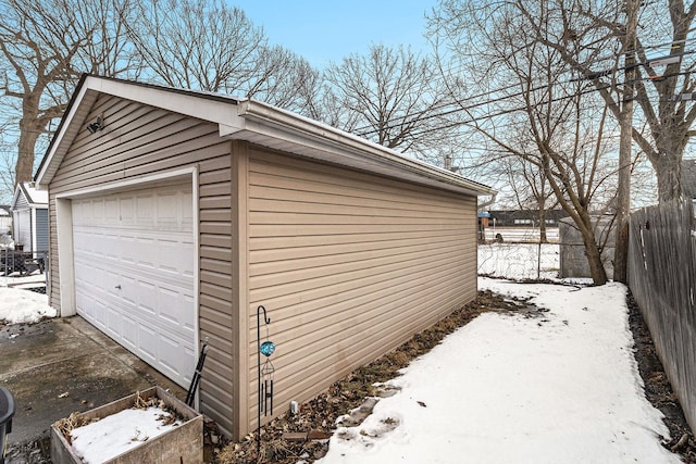 snow covered garage with a garage and fence