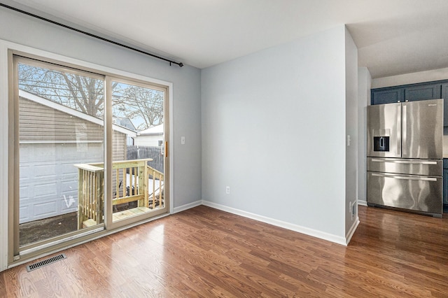 unfurnished dining area featuring wood finished floors, visible vents, and baseboards