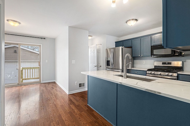 kitchen featuring dark wood finished floors, stainless steel appliances, visible vents, a sink, and light stone countertops