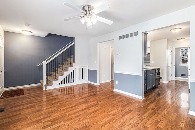 interior space featuring dark wood-type flooring, visible vents, stairway, and baseboards