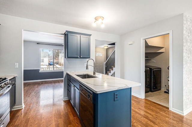 kitchen featuring dark wood finished floors, dishwasher, washer and dryer, a sink, and gas stove