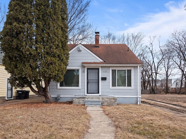 bungalow-style house featuring roof with shingles and a chimney