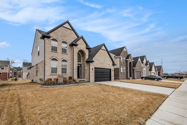 french country inspired facade featuring concrete driveway, brick siding, a front yard, and a residential view