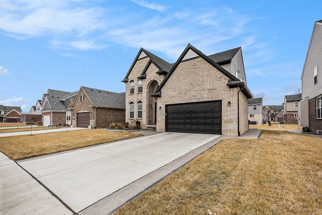 french country home featuring concrete driveway, brick siding, a front yard, and a residential view