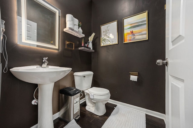 bathroom featuring toilet, baseboards, and wood finished floors