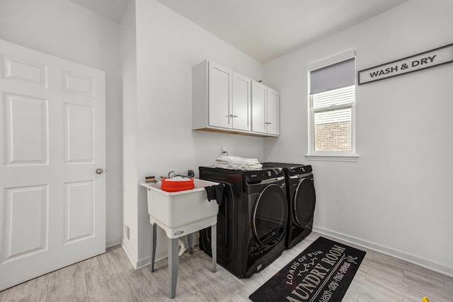 laundry area with baseboards, light wood-style flooring, cabinet space, and washer and dryer