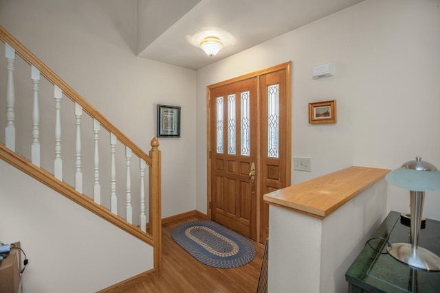 foyer entrance featuring stairs, baseboards, and wood finished floors