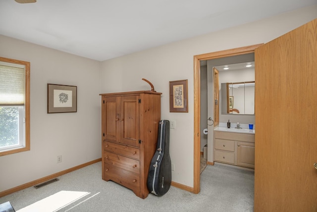 bedroom featuring light carpet, a sink, visible vents, and baseboards