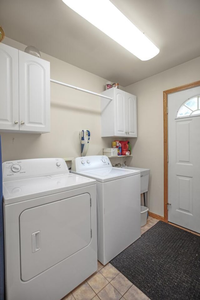 clothes washing area with cabinet space, light tile patterned floors, and separate washer and dryer