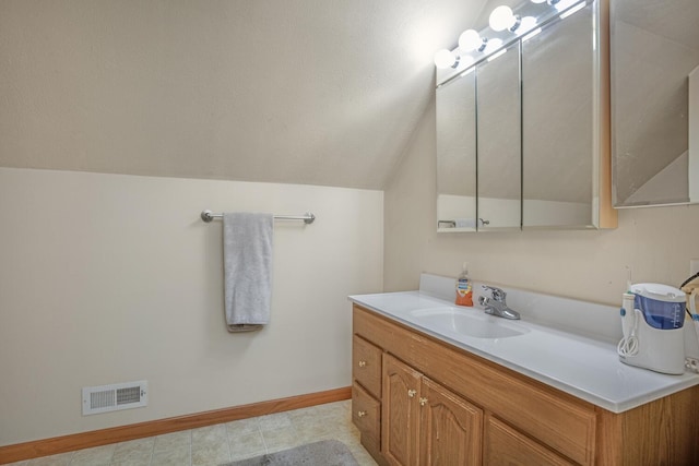 bathroom with baseboards, visible vents, lofted ceiling, a textured ceiling, and vanity