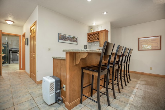 bar featuring a bar, light tile patterned floors, baseboards, and recessed lighting