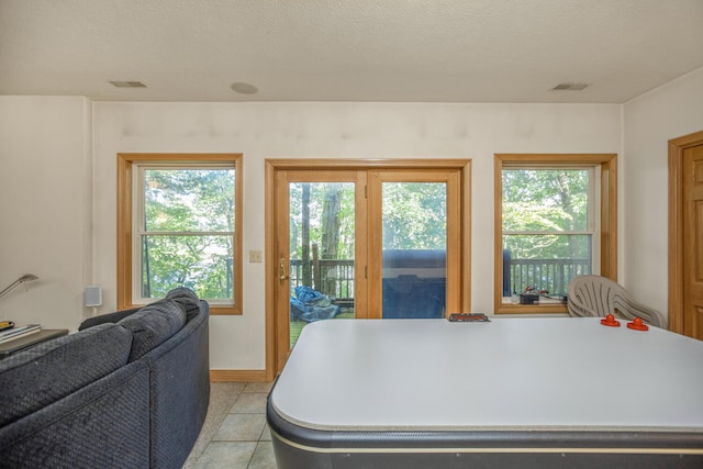 rec room with visible vents, a textured ceiling, baseboards, and light tile patterned floors