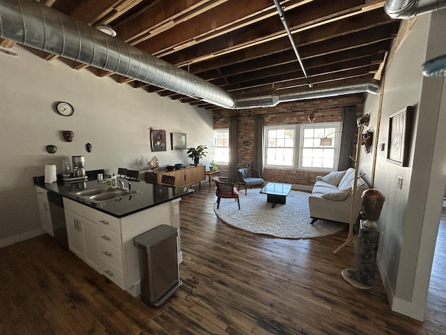 kitchen with white cabinets, dishwasher, dark countertops, open floor plan, and a sink