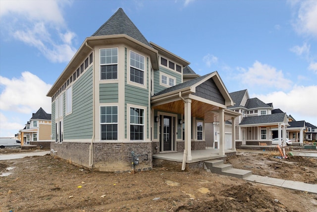 view of front facade featuring stone siding, a porch, and a shingled roof