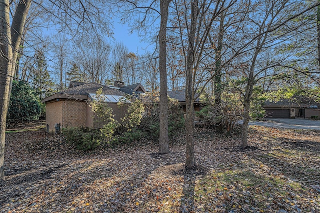 exterior space featuring a garage, brick siding, and a chimney