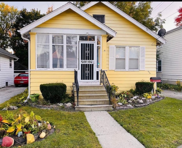 bungalow featuring entry steps and a front lawn