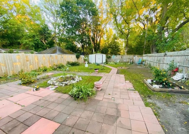 view of yard featuring a storage shed, a fenced backyard, an outbuilding, and a patio