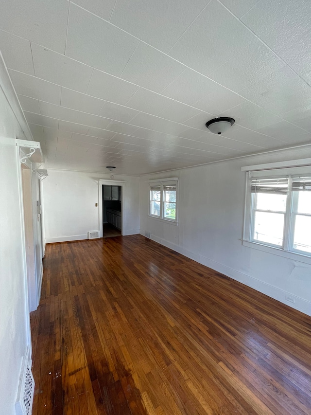 unfurnished living room featuring dark wood-style flooring, visible vents, and baseboards