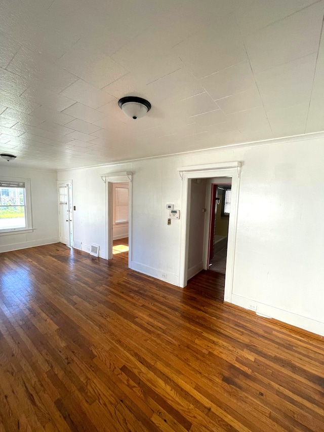 unfurnished room featuring visible vents, baseboards, and dark wood-style flooring