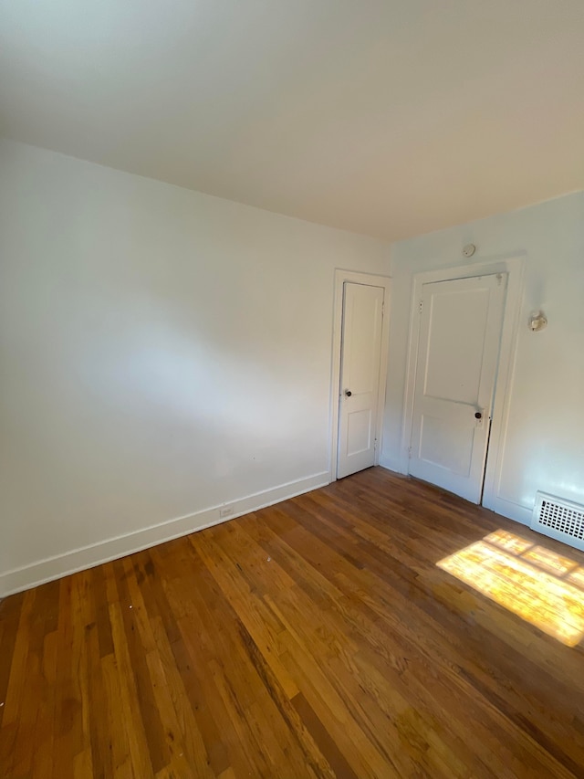 empty room featuring visible vents, baseboards, and wood finished floors