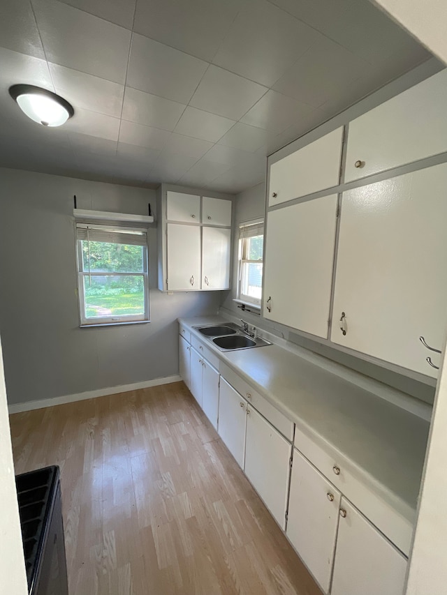 kitchen featuring light countertops, a healthy amount of sunlight, light wood-style floors, and white cabinets