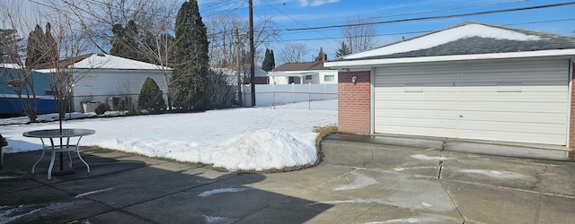 snowy yard featuring fence, a patio, and an outbuilding