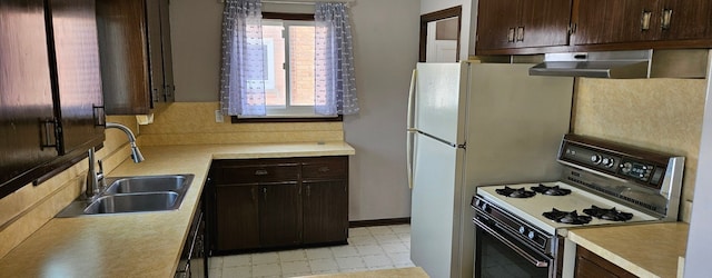 kitchen featuring white gas range oven, ventilation hood, light countertops, light floors, and a sink