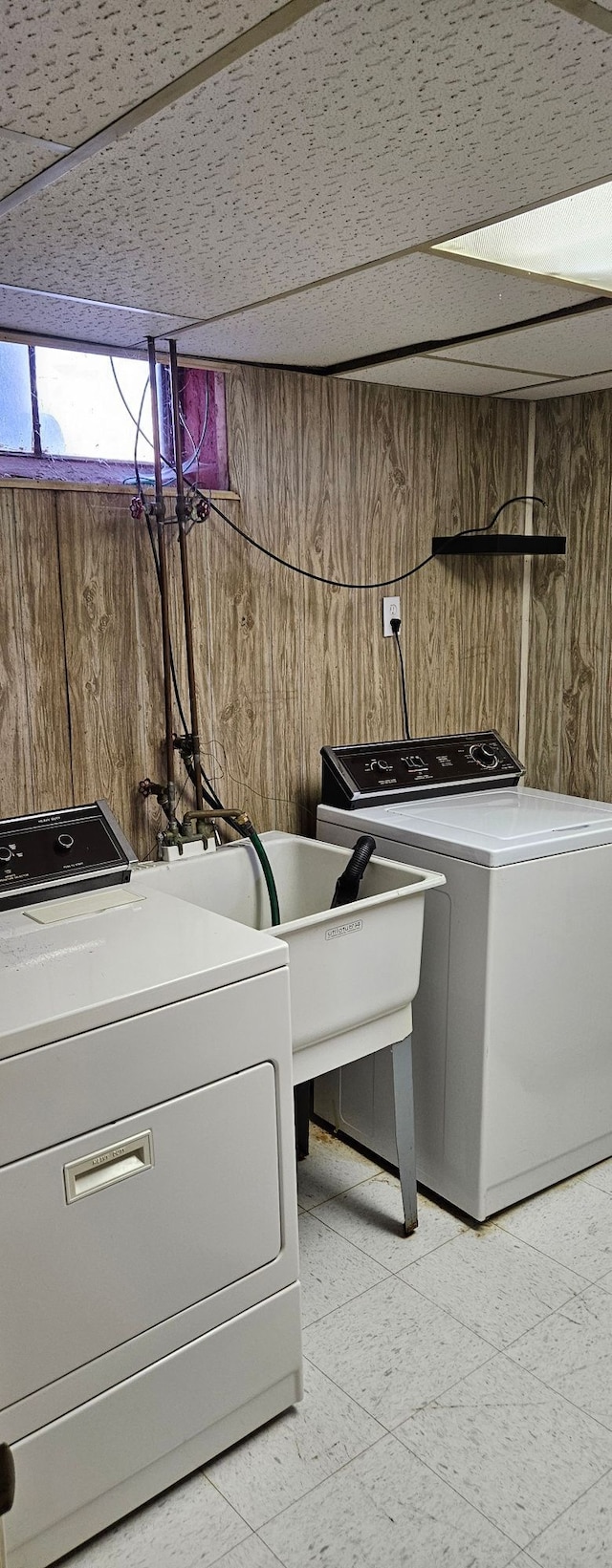 laundry area with light floors, wooden walls, and washer and dryer