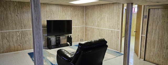 interior space with a drop ceiling, wood walls, visible vents, and tile patterned floors