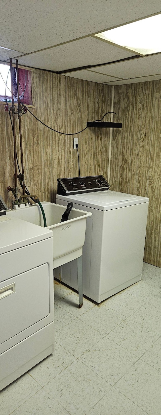 laundry room featuring laundry area, washing machine and clothes dryer, wooden walls, and light floors