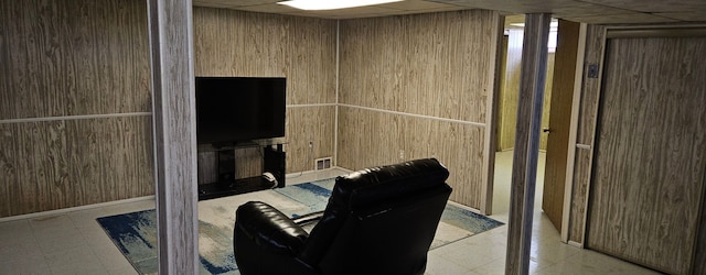 interior space with a paneled ceiling, visible vents, and wooden walls