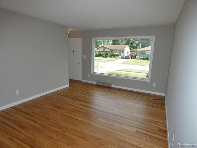 unfurnished room featuring light wood-type flooring, baseboards, and visible vents