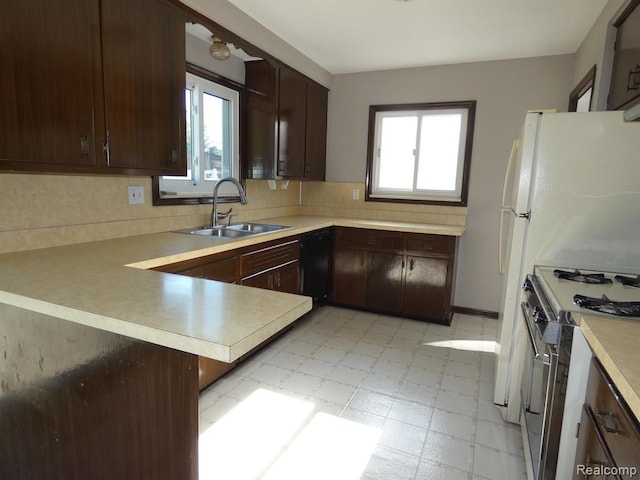 kitchen featuring light floors, light countertops, stainless steel gas stove, a sink, and a peninsula