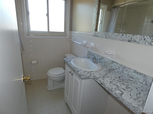 bathroom with curtained shower, vanity, toilet, and tile walls