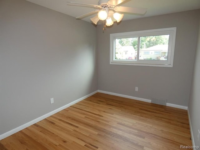 empty room featuring light wood-style floors, baseboards, visible vents, and a ceiling fan