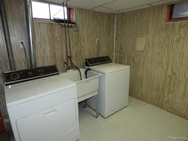 washroom featuring light floors, washing machine and dryer, a sink, wooden walls, and laundry area