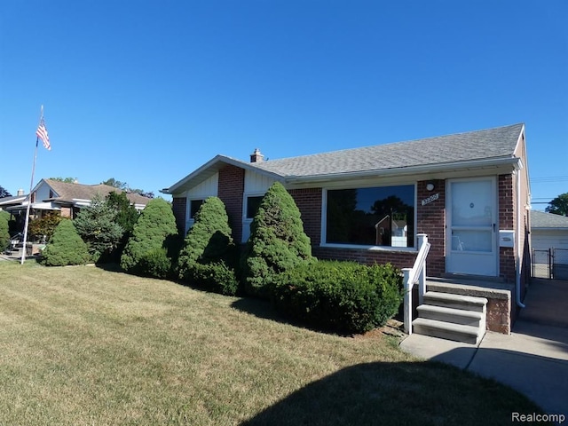 view of front of house with a shingled roof, a front lawn, and brick siding