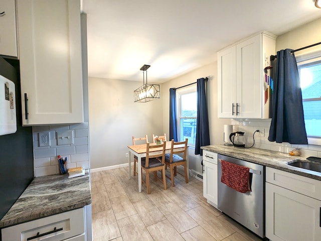 kitchen with hanging light fixtures, backsplash, stainless steel dishwasher, white cabinetry, and baseboards