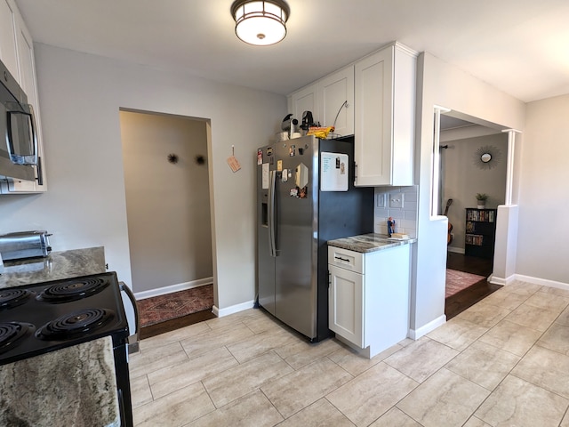 kitchen with tasteful backsplash, baseboards, white cabinets, dark stone counters, and appliances with stainless steel finishes