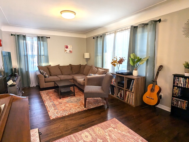 living area with dark wood-style flooring, a wealth of natural light, and baseboards