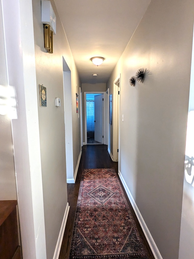 hallway with dark wood finished floors and baseboards