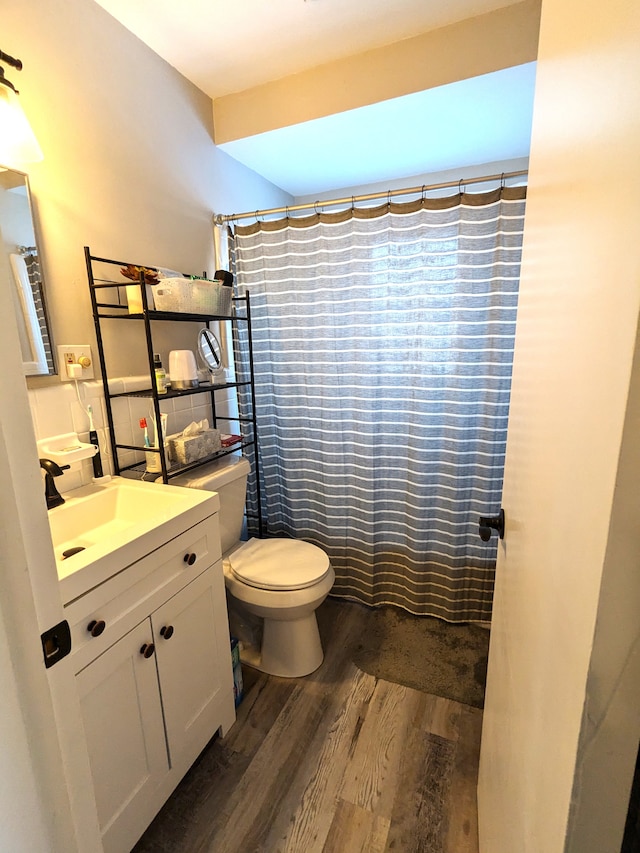 full bath featuring toilet, curtained shower, wood finished floors, and vanity