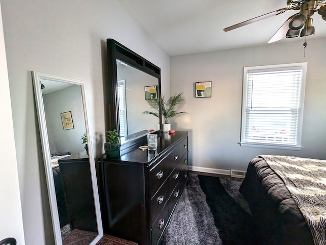 bedroom with ceiling fan, dark carpet, visible vents, and baseboards