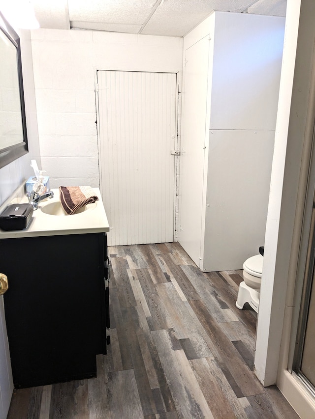 bathroom featuring concrete block wall, vanity, toilet, and wood finished floors